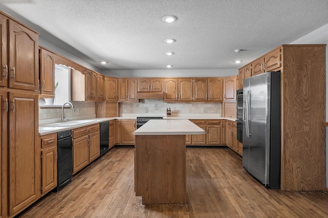 kitchen with stainless steel refrigerator with ice dispenser, a sink, dark wood-style flooring, a textured ceiling, and recessed lighting