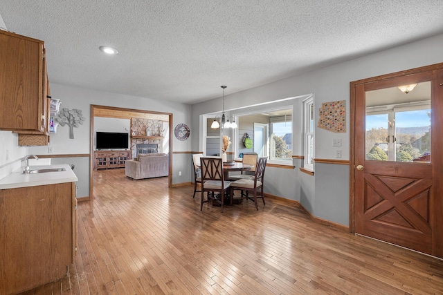 dining area with a textured ceiling, healthy amount of natural light, a chandelier, light wood-type flooring, and baseboards