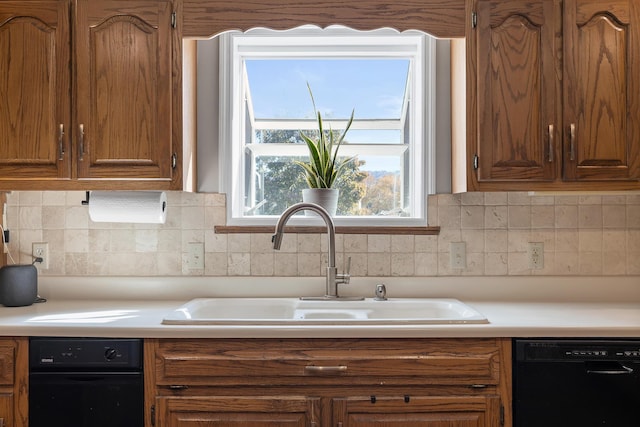 kitchen featuring dishwasher, a sink, light countertops, and backsplash