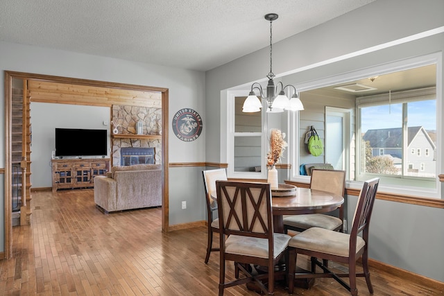dining space with baseboards, hardwood / wood-style floors, a chandelier, and a textured ceiling