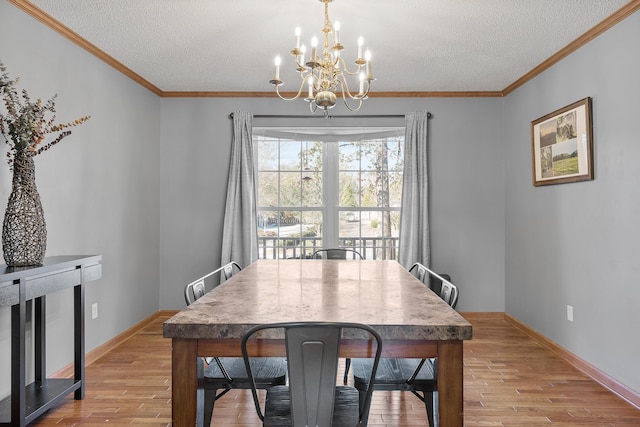 dining room featuring a chandelier, wood finished floors, a textured ceiling, ornamental molding, and baseboards