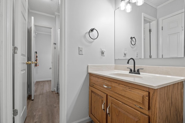 bathroom featuring ornamental molding, wood finished floors, vanity, and baseboards