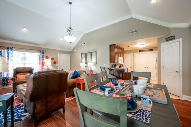 dining room featuring vaulted ceiling, crown molding, wood finished floors, and baseboards