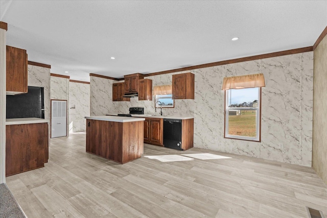 kitchen with black appliances, light countertops, light wood finished floors, a center island, and under cabinet range hood
