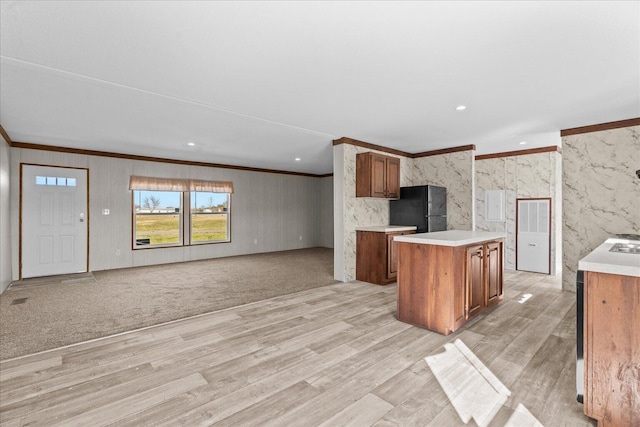 kitchen featuring freestanding refrigerator, crown molding, light countertops, light wood finished floors, and brown cabinets