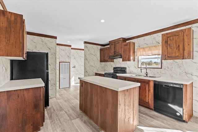 kitchen with black appliances, a sink, under cabinet range hood, a center island, and light countertops