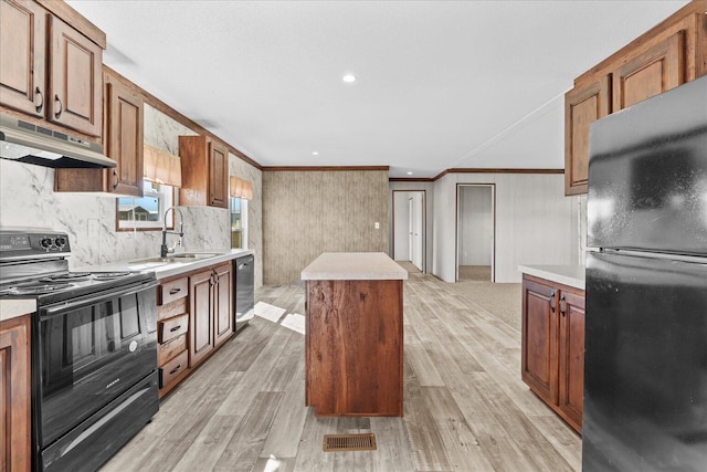 kitchen with black appliances, under cabinet range hood, a sink, crown molding, and a kitchen island