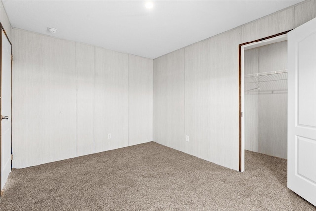 unfurnished bedroom featuring carpet floors, a spacious closet, and a closet
