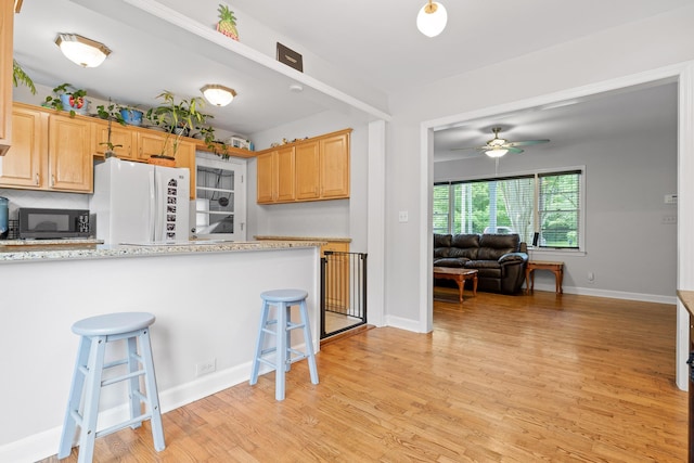 5007 Florida Ave, Chattanooga, TN 37409 - kitchen featuring freestanding refrigerator, black microwave, a breakfast bar, a ceiling fan, and light wood finished floors