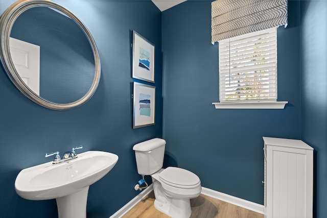 bathroom with wood finished floors, baseboards, toilet, and a sink