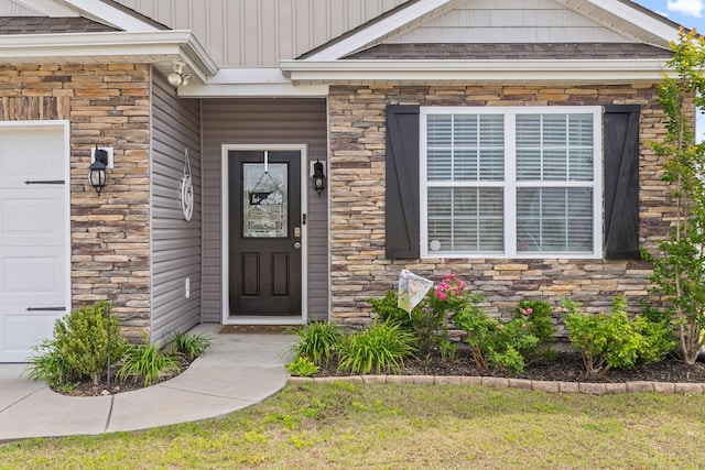 view of exterior entry with stone siding and an attached garage