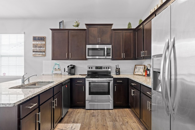 kitchen with appliances with stainless steel finishes, a sink, a peninsula, and tasteful backsplash