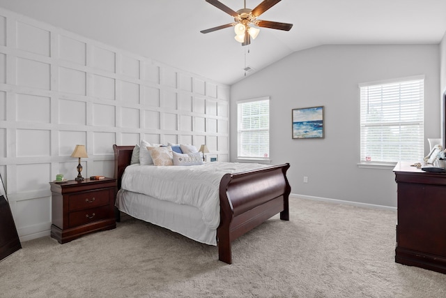 bedroom featuring vaulted ceiling, light carpet, a decorative wall, baseboards, and ceiling fan