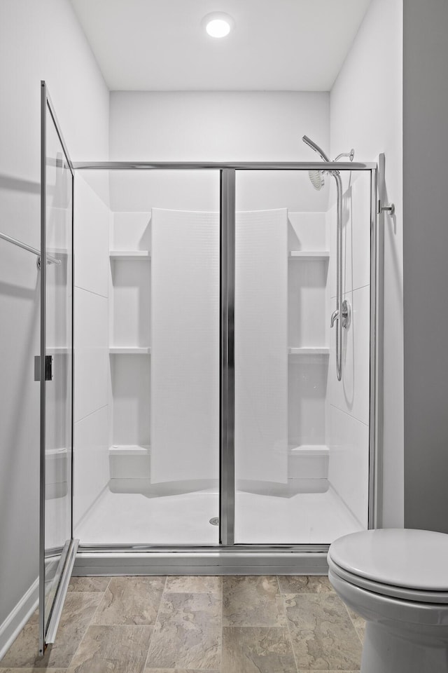 full bathroom with a shower stall, toilet, and stone finish floors