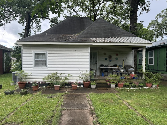 view of front facade with a front yard, central AC, and a shingled roof