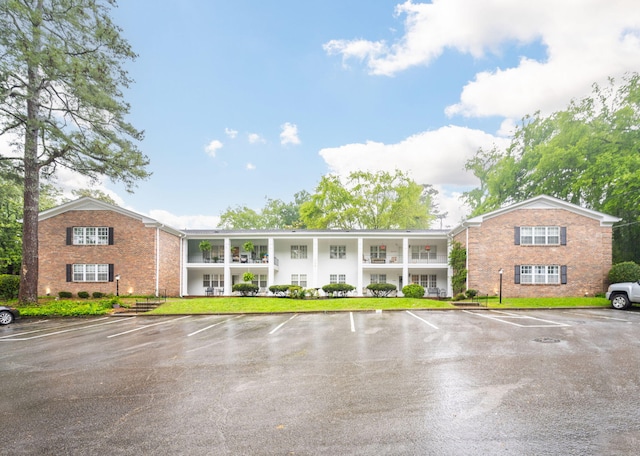 view of front of house with uncovered parking, brick siding, and a front lawn