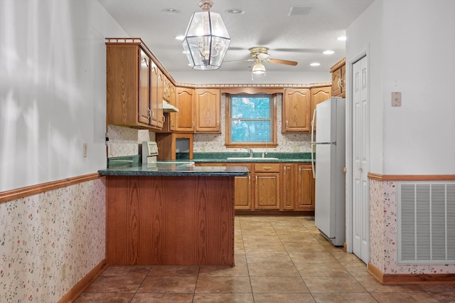 6601 Hunter Rd, Harrison, TN 37341 - kitchen with freestanding refrigerator, a peninsula, dark countertops, ceiling fan, and wallpapered walls
