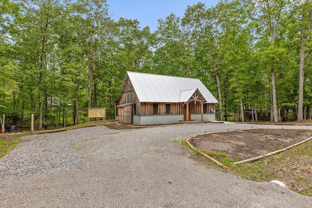 view of front of house with a garage, metal roof, and driveway