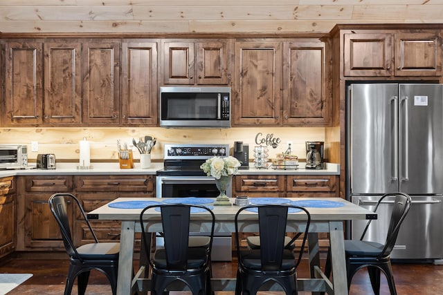 kitchen with appliances with stainless steel finishes, a kitchen bar, and light countertops