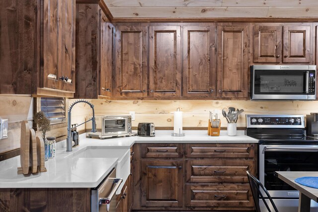 kitchen with appliances with stainless steel finishes, light countertops, and dark brown cabinets