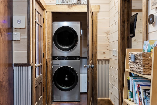 clothes washing area with estacked washer and dryer and wooden walls