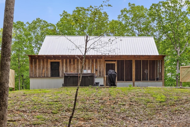 back of house with a hot tub, a sunroom, and metal roof