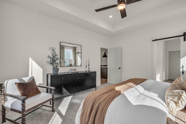 bedroom with a barn door, light carpet, and ceiling fan