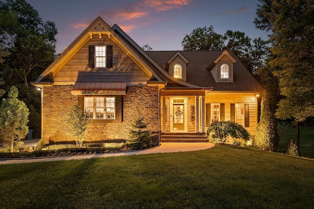 view of front facade featuring stone siding, a yard, and a standing seam roof