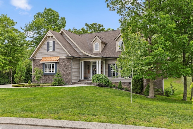 view of front facade featuring a front lawn, roof with shingles, and stone siding