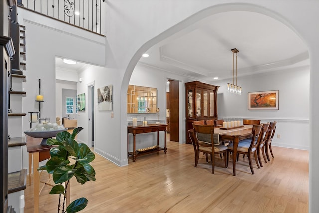 dining area featuring arched walkways, ornamental molding, light wood-style floors, recessed lighting, and baseboards