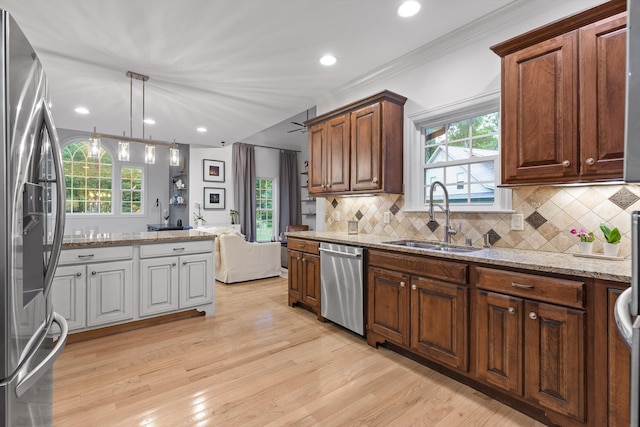 kitchen featuring stainless steel appliances, a sink, light wood finished floors, decorative backsplash, and recessed lighting