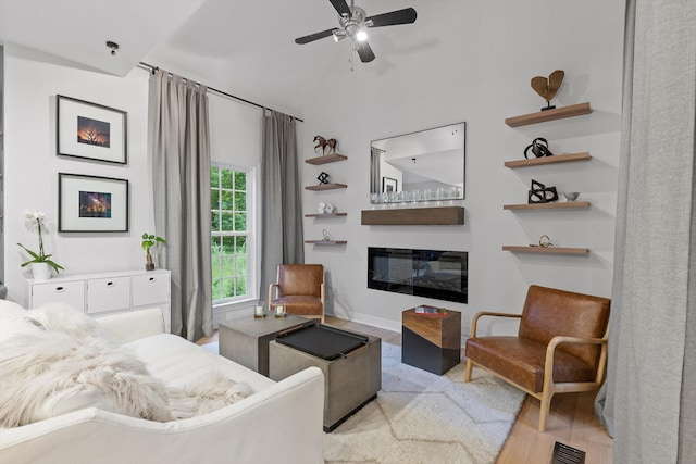 bedroom featuring light wood-style flooring and a glass covered fireplace