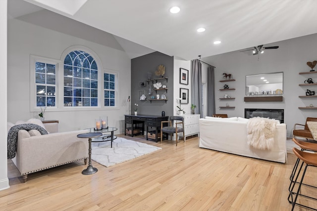 living area featuring lofted ceiling, wood finished floors, a glass covered fireplace, recessed lighting, and ceiling fan