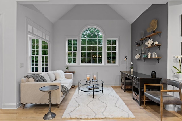 living area featuring light wood-style flooring, lofted ceiling, and baseboards