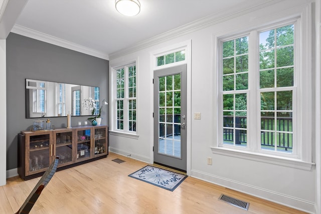 doorway featuring wood finished floors, baseboards, plenty of natural light, and crown molding