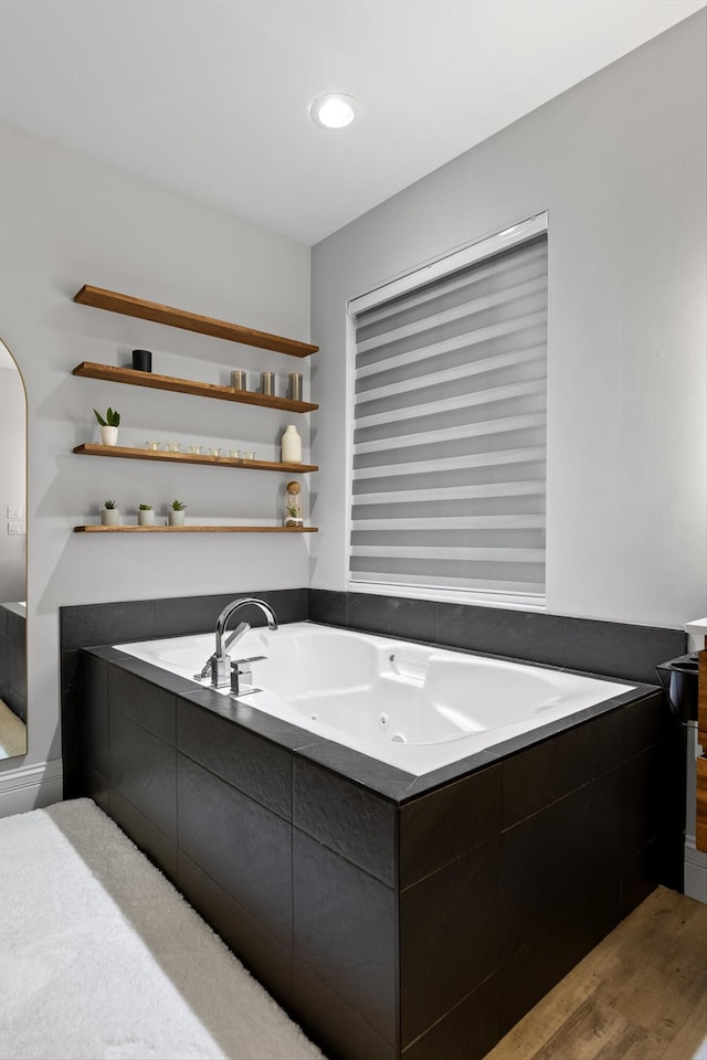 full bath featuring a tub with jets and wood finished floors