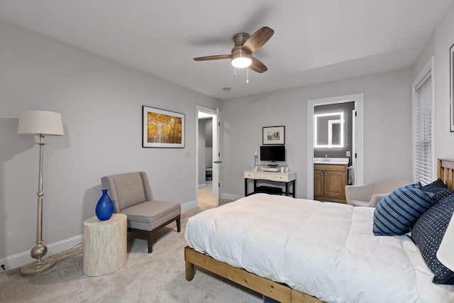 bedroom featuring light carpet, baseboards, a sink, ensuite bath, and a ceiling fan
