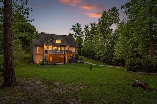 back of property at dusk with a yard, a deck, and stairway