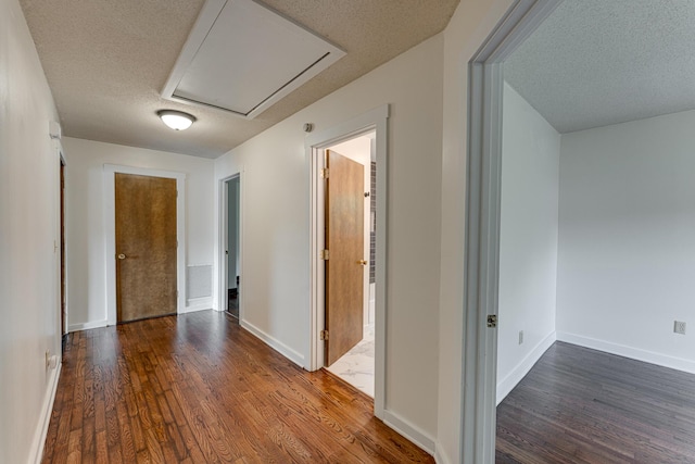 hallway featuring wood finished floors, a textured ceiling, and baseboards