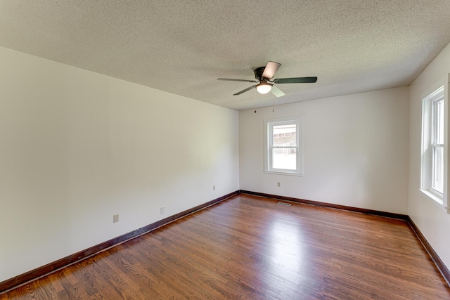 empty room featuring dark wood-style floors, baseboards, a textured ceiling, and a ceiling fan