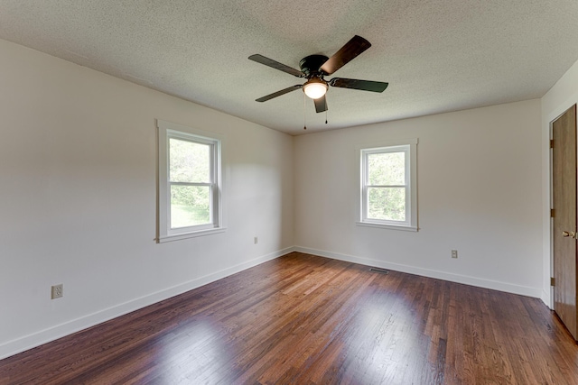 empty room with healthy amount of natural light, a textured ceiling, wood finished floors, ceiling fan, and baseboards