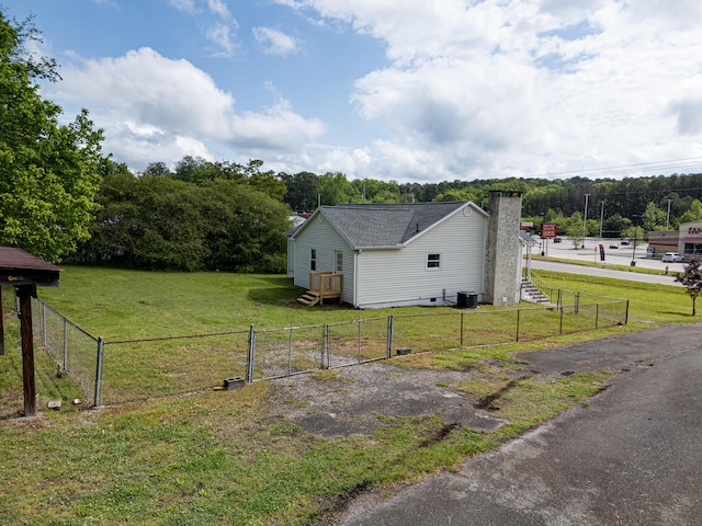 view of side of home with central AC unit, a gate, and a chimney