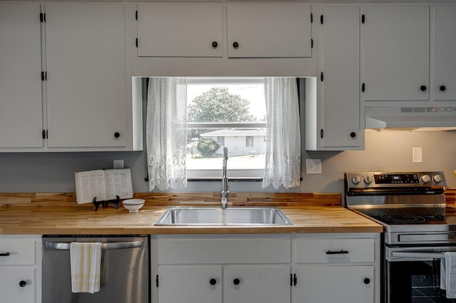 kitchen with stainless steel appliances, under cabinet range hood, a sink, butcher block counters, and white cabinetry