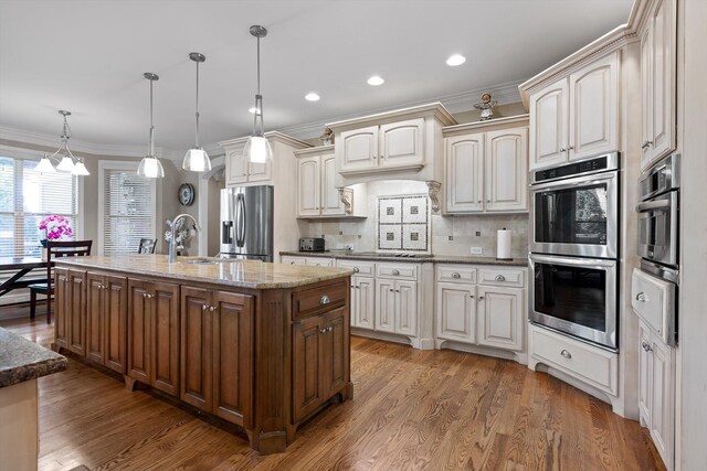 8109 Propeller Dr, Ooltewah, TN 37363 - kitchen with stainless steel appliances, a sink, ornamental molding, an island with sink, and wood finished floors