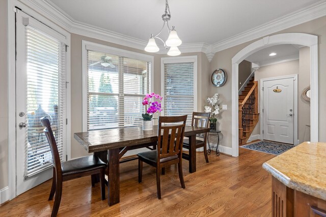 8109 Propeller Dr, Ooltewah, TN 37363 - dining space with crown molding, arched walkways, stairway, a chandelier, and light wood-style flooring