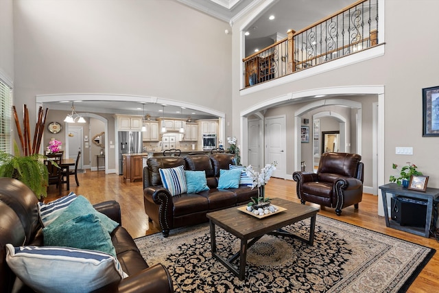 8109 Propeller Dr, Ooltewah, TN 37363 - living room featuring arched walkways, a high ceiling, ornamental molding, light wood finished floors, and baseboards