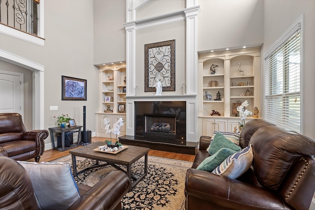 8109 Propeller Dr, Ooltewah, TN 37363 - living area featuring a towering ceiling, wood finished floors, a fireplace, decorative columns, and baseboards