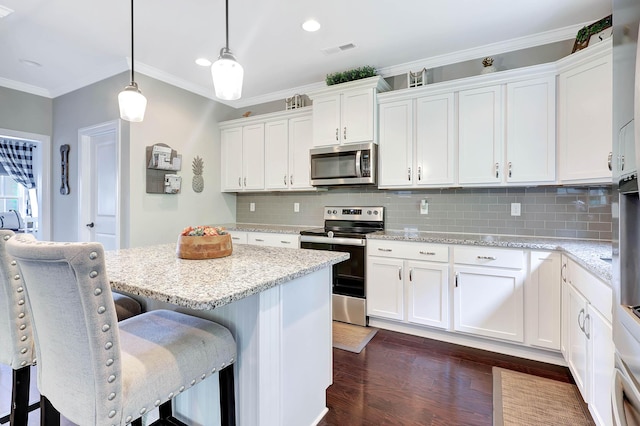 5479 Amber Grove Way, Hixson, TN 37343 - kitchen with stainless steel appliances, white cabinets, dark wood-style flooring, ornamental molding, and a breakfast bar