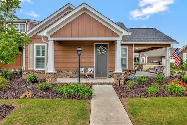 craftsman house with covered porch, board and batten siding, a front yard, and brick siding