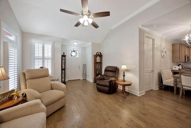 living area with lofted ceiling, ceiling fan, a chandelier, wood finished floors, and baseboards